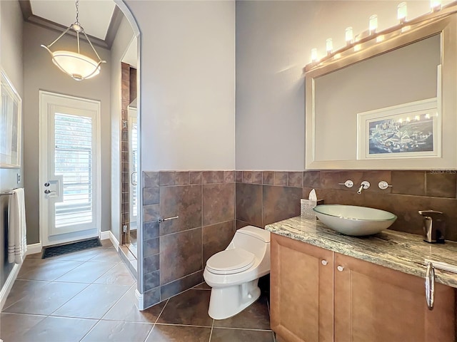 bathroom featuring tile patterned floors, toilet, a shower with shower door, tile walls, and vanity