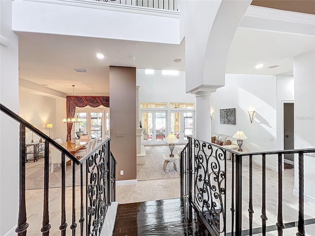 stairs with french doors, tile patterned floors, and decorative columns