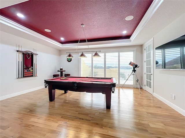 rec room featuring billiards, a textured ceiling, light wood-type flooring, and a tray ceiling