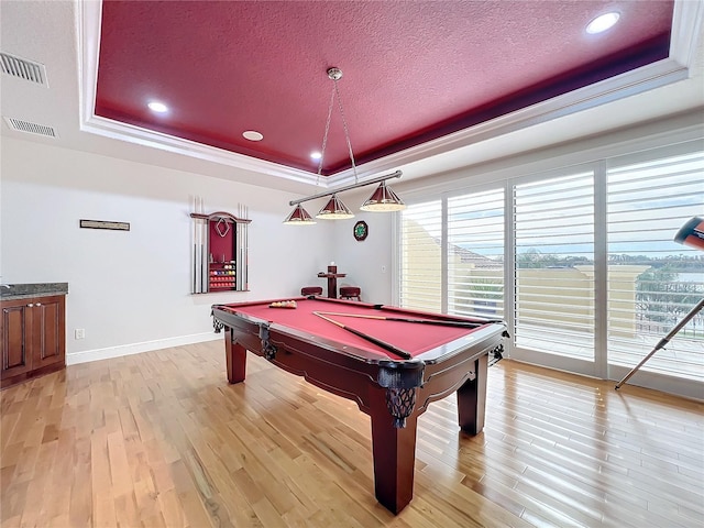 rec room with pool table, a raised ceiling, light hardwood / wood-style flooring, and a textured ceiling