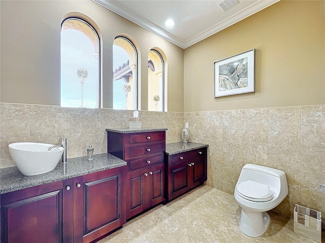 bathroom with crown molding, vanity, toilet, and tile walls