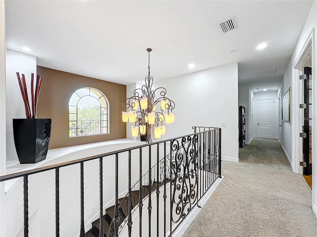 hallway featuring light colored carpet and an inviting chandelier