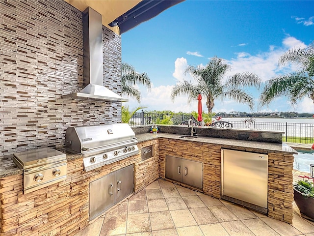 view of patio with exterior kitchen, a water view, a grill, and sink