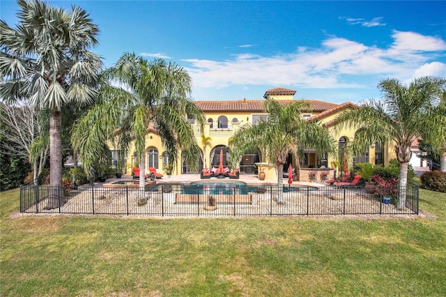 rear view of property featuring a fenced in pool, a patio, and a yard