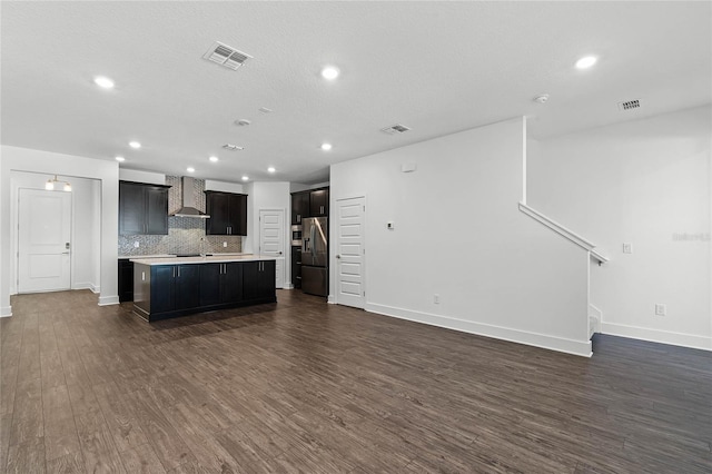 kitchen featuring visible vents, stainless steel refrigerator with ice dispenser, dark wood-style floors, open floor plan, and wall chimney range hood