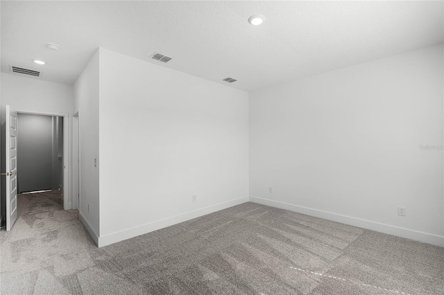 unfurnished room with baseboards, visible vents, and light carpet