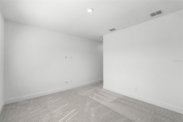 carpeted empty room with baseboards, visible vents, and a textured ceiling