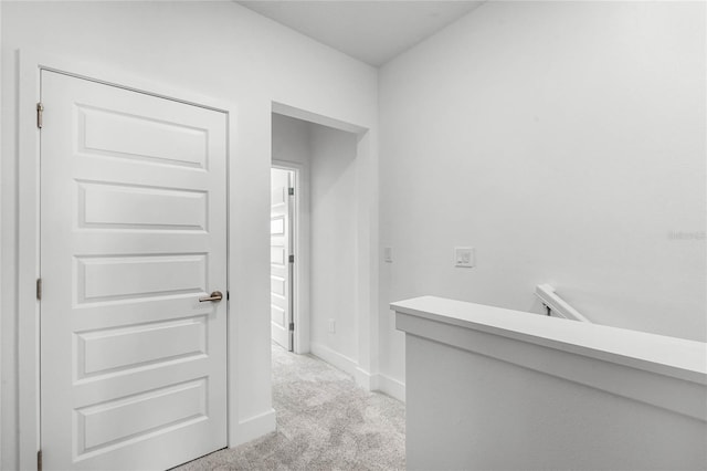 hall with light colored carpet and baseboards