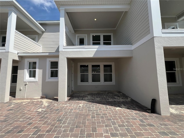 view of exterior entry with a patio area and stucco siding