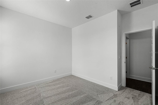 unfurnished bedroom featuring baseboards, visible vents, carpet floors, and a textured ceiling