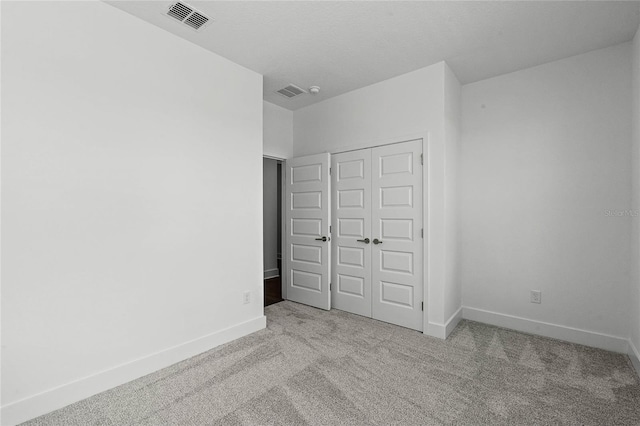 unfurnished bedroom with carpet, visible vents, a closet, and baseboards