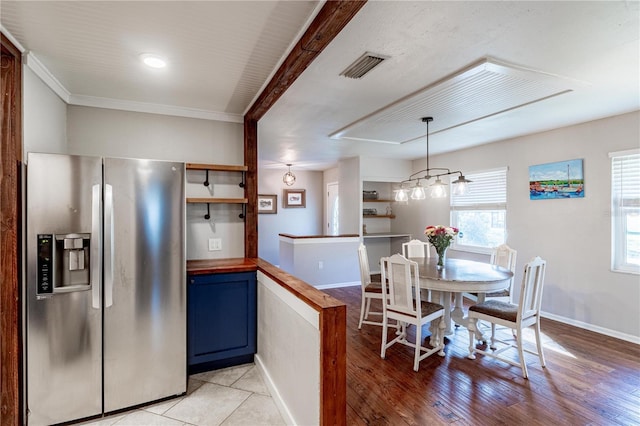 kitchen featuring hanging light fixtures, ornamental molding, stainless steel fridge, and light hardwood / wood-style flooring