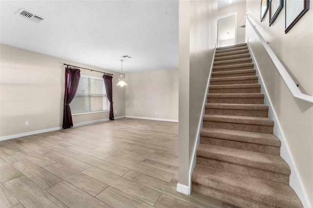 stairway featuring a textured ceiling