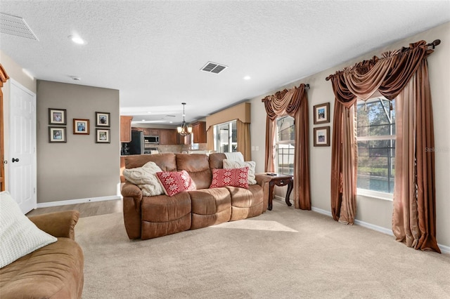 living room featuring a chandelier, light carpet, and a textured ceiling