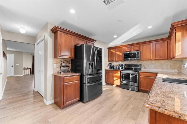 kitchen featuring sink, light hardwood / wood-style flooring, appliances with stainless steel finishes, light stone counters, and tasteful backsplash