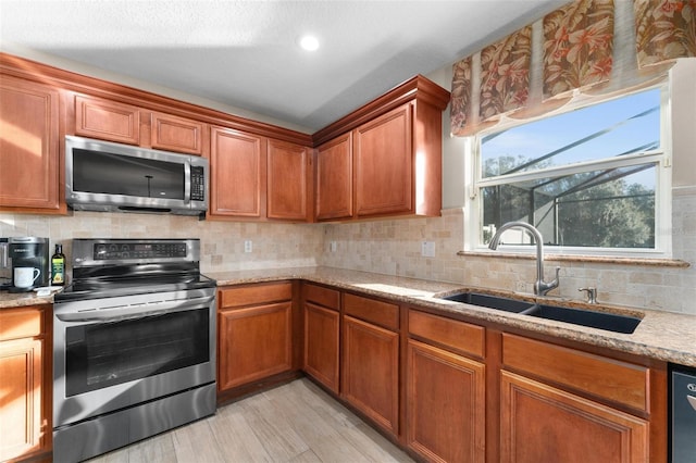 kitchen with light stone counters, stainless steel appliances, light hardwood / wood-style floors, and sink