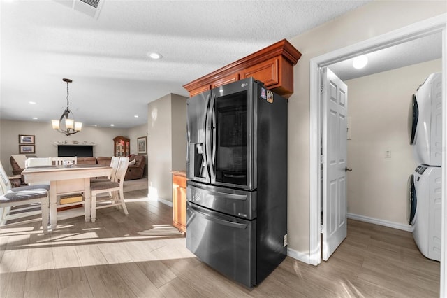 kitchen with pendant lighting, stacked washer / dryer, stainless steel fridge, a textured ceiling, and light hardwood / wood-style flooring