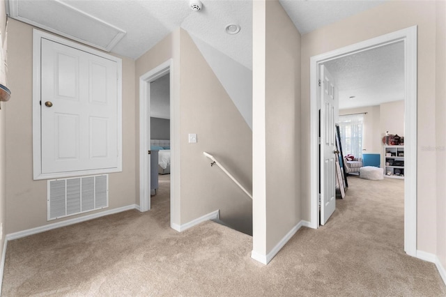 corridor featuring light colored carpet and a textured ceiling