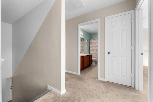 hall with light carpet and a textured ceiling