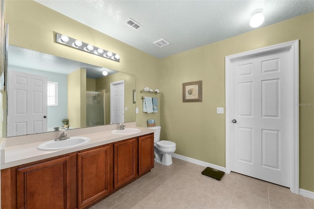 bathroom with tile patterned flooring, vanity, a textured ceiling, a shower with shower door, and toilet