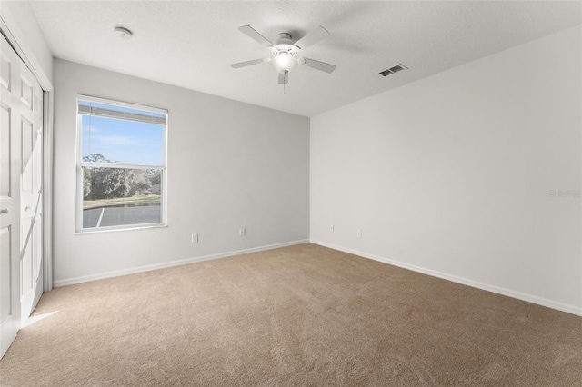 carpeted empty room featuring ceiling fan and a textured ceiling