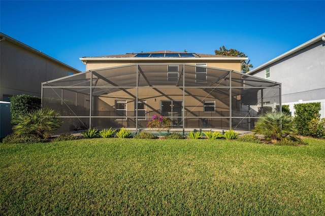 back of property with solar panels and a lawn