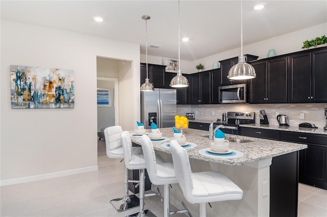 kitchen with appliances with stainless steel finishes, pendant lighting, sink, a kitchen island with sink, and light tile patterned floors