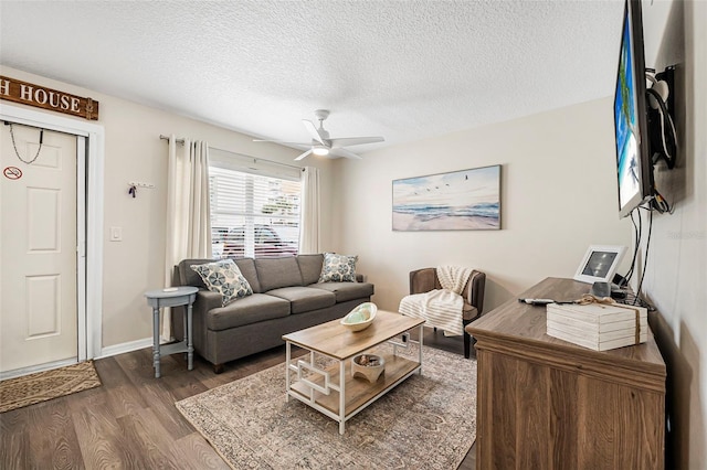 living room featuring ceiling fan, dark wood-type flooring, and a textured ceiling