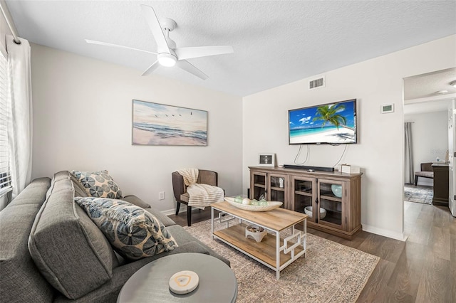 living room featuring ceiling fan, dark hardwood / wood-style floors, and a textured ceiling