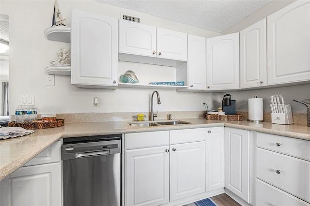 kitchen with sink, wood-type flooring, a textured ceiling, stainless steel dishwasher, and white cabinets