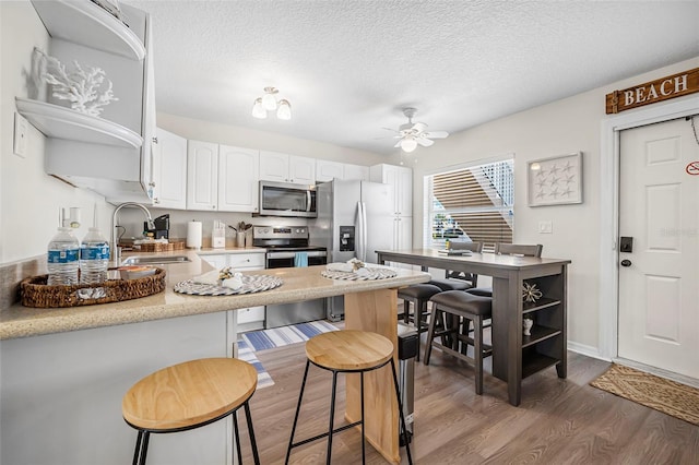 kitchen with white cabinetry, appliances with stainless steel finishes, sink, and a kitchen bar