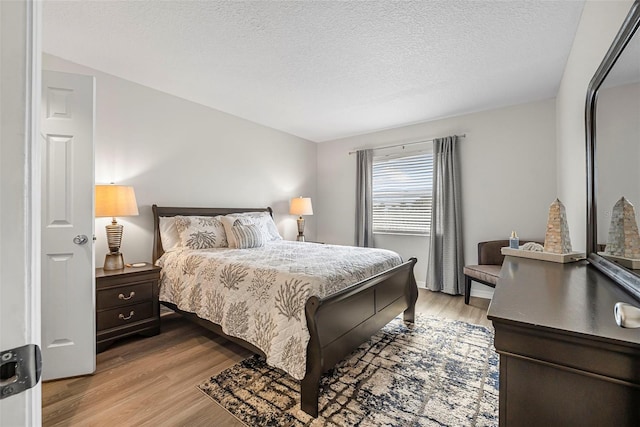 bedroom with light hardwood / wood-style floors and a textured ceiling