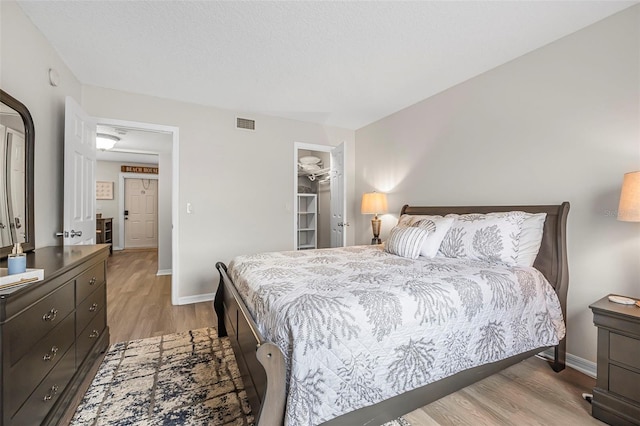 bedroom featuring a spacious closet, light hardwood / wood-style floors, and a closet