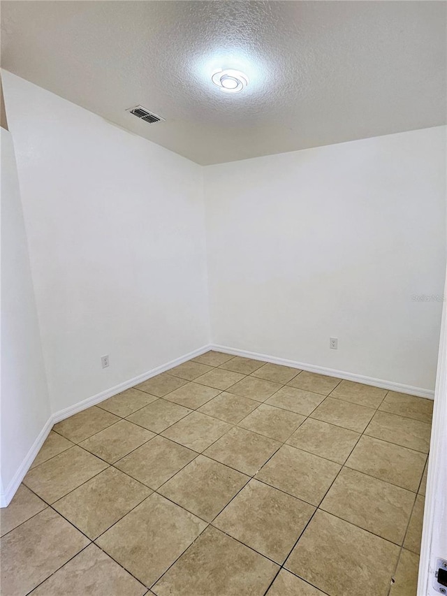 tiled spare room with a textured ceiling