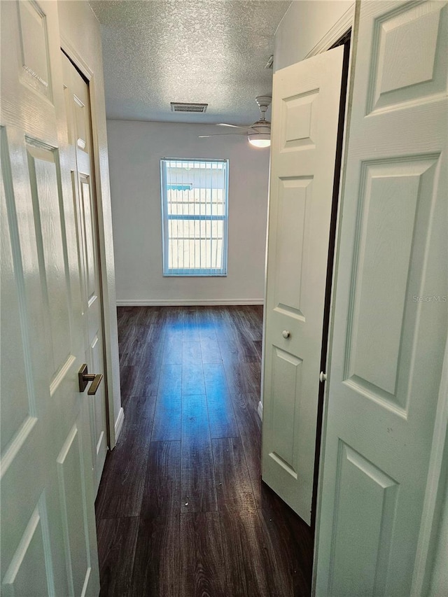 hallway featuring dark wood-type flooring and a textured ceiling