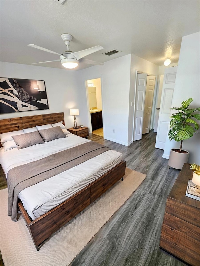 bedroom featuring ceiling fan, ensuite bathroom, dark hardwood / wood-style floors, and a textured ceiling