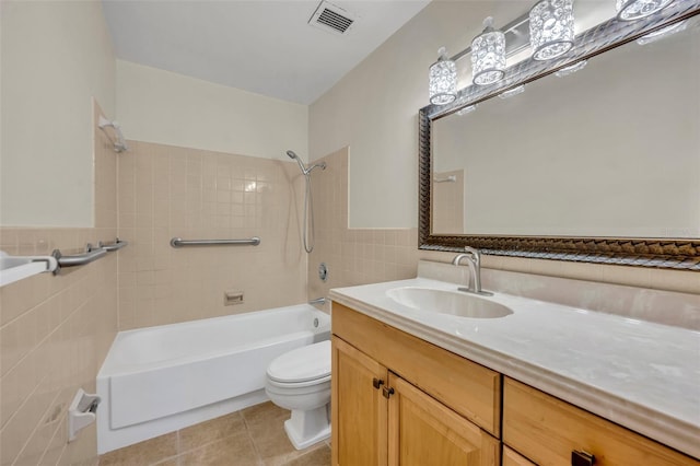 full bathroom with tile walls, tile patterned flooring, vanity, toilet, and tiled shower / bath