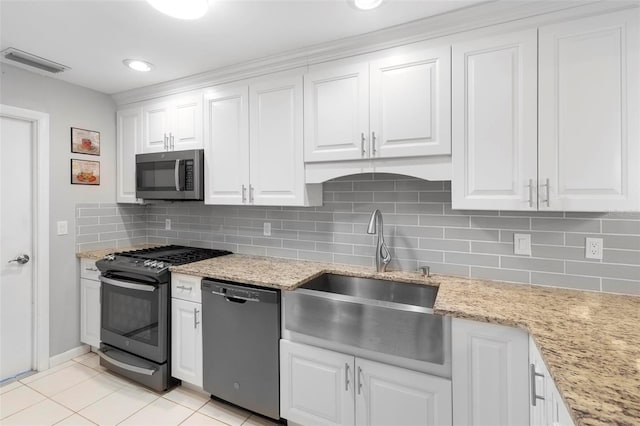 kitchen featuring sink, light tile patterned floors, white cabinetry, backsplash, and stainless steel appliances