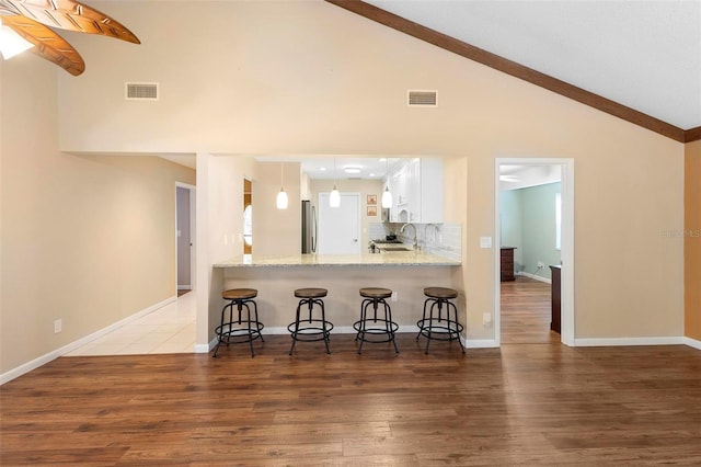 kitchen featuring white cabinetry, stainless steel fridge, kitchen peninsula, and decorative backsplash