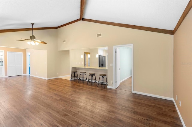 unfurnished living room featuring dark hardwood / wood-style flooring, vaulted ceiling with beams, and ceiling fan