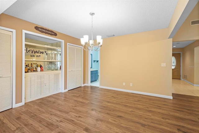 unfurnished dining area with an inviting chandelier, hardwood / wood-style floors, and a textured ceiling