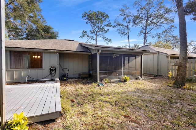 rear view of property with a sunroom, a deck, and a lawn