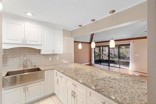 kitchen featuring decorative light fixtures, tasteful backsplash, sink, white cabinets, and kitchen peninsula