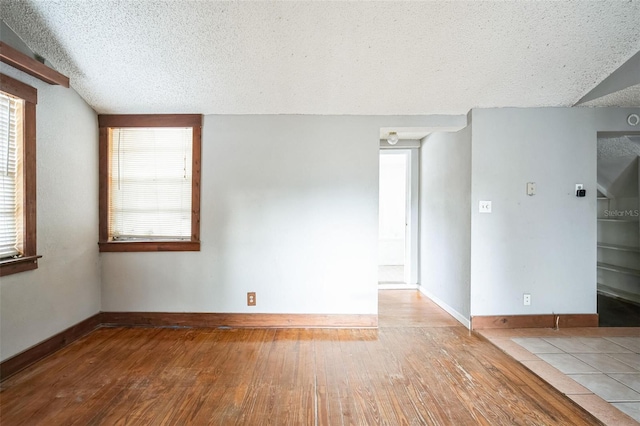 unfurnished room featuring a healthy amount of sunlight, light hardwood / wood-style floors, and a textured ceiling