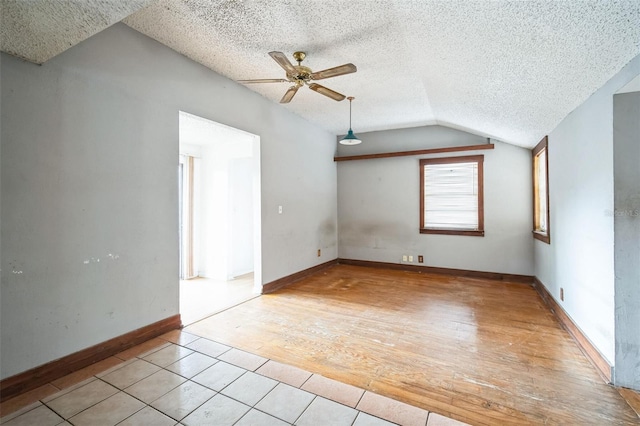 interior space with ceiling fan, lofted ceiling, a textured ceiling, and light tile patterned floors