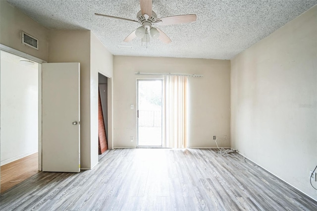 empty room with ceiling fan, light hardwood / wood-style flooring, and a textured ceiling