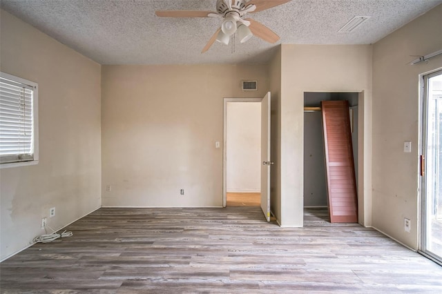 unfurnished bedroom featuring ceiling fan, a textured ceiling, and light wood-type flooring