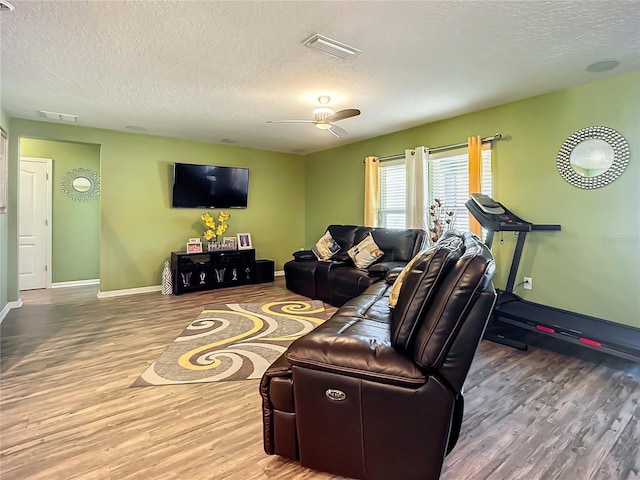 living room with ceiling fan, hardwood / wood-style flooring, and a textured ceiling