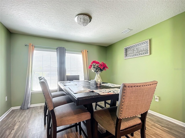 dining room featuring a healthy amount of sunlight, hardwood / wood-style floors, and a textured ceiling