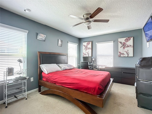 bedroom featuring multiple windows, ceiling fan, light carpet, and a textured ceiling